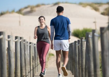A couple enjoys jogging on a sunny beach boardwalk in Portugal, capturing a moment of fitness and leisure.